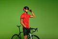 Young sportsman, cyclist on bicycle in sports uniform and protective helmet training isolated on green background