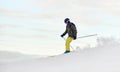 Skier descending from snow-covered high mountain top. Extreme skiing concept. Mountains view. Winter sky on background.