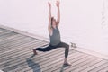 Young sportsman performing articular movements of yoga in an urban area of the city