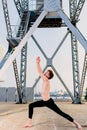 Young sportsman performing articular movements of yoga in an urban area of the city