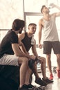 young sportsmen sitting on tire and talking after workout
