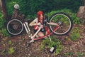 Young sportswoman bicyclist repairing her mtb bike in the forest