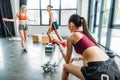 young sportswoman doing exercise with dumbbell while two female athletes training behind