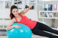 Young sportswoman doing exercises with ball and dumbbells