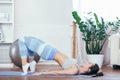 Young sportswoman doing exercises with ball on a mat at home