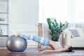 Young sportswoman doing exercises with ball on a mat at home