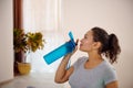 Young sportswoman drinking water after hard workout. Rehydration concept