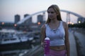 Young sportswoman after evening workout, holding a water bottle