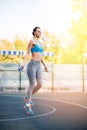 Young sportswoman exercising with skipping rope on stadium