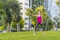 Young sportswoman performing exercises on the grass in a city