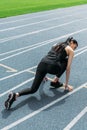Young sportswoman in starting position on running track stadium Royalty Free Stock Photo