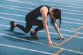 Young sportswoman in starting position on running track stadium Royalty Free Stock Photo