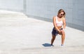 Young sportswoman stretching and preparing to run. listens to the music on mobile app.