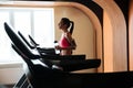 Young sportswoman walking on treadmill and drinking water in gym Royalty Free Stock Photo