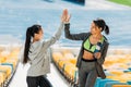 Young sportswomen with sport bottle giving highfive on stadium stairs