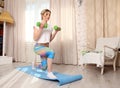 Young sporty attractive woman practicing fitness concept, doing squats exercise with dumbbells, working out wearing sportswear, fu Royalty Free Stock Photo