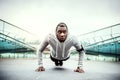 Young sporty black man runner doing push-ups on the bridge outside in a city.