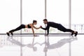 Young sporty couple working out together in a gym doing plank exercises while holding each other for one hand Royalty Free Stock Photo