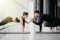 Young sporty couple working out together in a gym doing plank exercises while holding each other for one hand Royalty Free Stock Photo