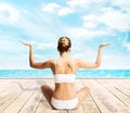 Sporty, young and beautiful woman in swimsuit meditating on a pier at summer. Sport and yoga concept. Royalty Free Stock Photo