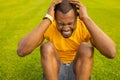 Young sporty focused Afro American male lying on green grass doing morning workout outdoors, healthy positive active Royalty Free Stock Photo