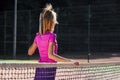 Young sporty girl dressed pink sportswear with racket on the shoulder stands near net on outdoor tennis court. Royalty Free Stock Photo
