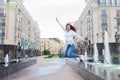 Young sporty girl jumping for joy at the fountain in the residential complex. Female in flight with his hands up Royalty Free Stock Photo