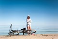 Young sporty lady resting from riding bicycle on the beach