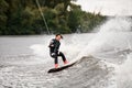 Young sporty girl in wetsuit actively rides waves on wakeboard on the river Royalty Free Stock Photo