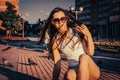 Young sporty lady is posing sitting on alley with birds walking on background wind swept hair sunlit image Royalty Free Stock Photo