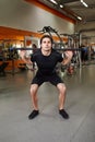 Young sporty man in the black sportwear with barbell doing squats in gym. Royalty Free Stock Photo