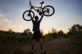 A young sporty man is holding a bicycle at sunset Royalty Free Stock Photo