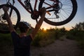 A young sporty man is holding a bicycle at sunset Royalty Free Stock Photo