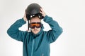 Man with goggles putting on ski helmet