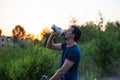 Young sporty man riding a bicycle drinking water from the sport bottle at sunset Royalty Free Stock Photo