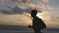 Young sporty man running on the sea beach at sunset. Athletic guy jogging along ocean shore during sunrise. Male Royalty Free Stock Photo