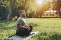 Young sporty man yogi sitting in lotus yoga pose in grass lawn park outdoors