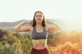 Young sporty woman demonstrates the inflated muscles of the arms. In the background there is a forest and a view of the city.