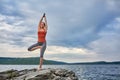 Young sporty woman doing different variants of yoga position on a rocky rivershore.