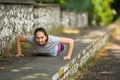 Young sporty woman doing push-ups in park in sunshine on beautiful summer day. Royalty Free Stock Photo