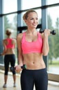 Young sporty woman with dumbbells flexing biceps
