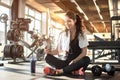Young sporty woman listening to music on smartphone in gym. Break after hard workout. Royalty Free Stock Photo