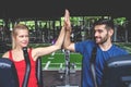 Young sporty woman and man giving each other a high five after cycling training in gym. Fit couple high five after workout Royalty Free Stock Photo