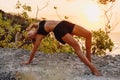 Young woman doing yoga in outdoor at warm sunset and ocean on background Royalty Free Stock Photo