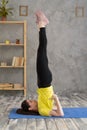 Young sporty woman practicing yoga at home, doing Salamba Sarvangasana exercise, supported shoulder stand pose. Royalty Free Stock Photo