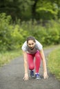 Young sporty woman ready to start running in the park in sunshine on beautiful summer day. Royalty Free Stock Photo