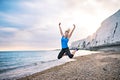 Young sporty woman runner in blue sportswear jumping on the beach outside. Royalty Free Stock Photo