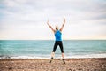 Young sporty woman runner in blue sportswear jumping on the beach outside. Royalty Free Stock Photo