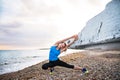 Young sporty woman runner in blue sportswear stretching on the beach outside. Royalty Free Stock Photo