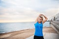 Young sporty woman runner with earphones standing on the beach outside, stretching. Royalty Free Stock Photo